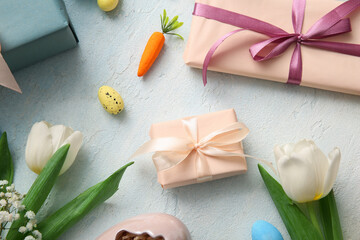 Easter eggs with flowers and gift boxes on blue grunge background