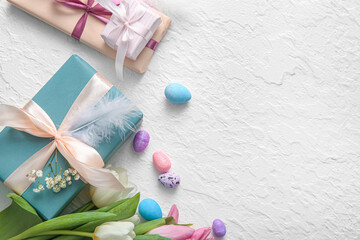 Easter eggs with gift boxes and flowers on white background