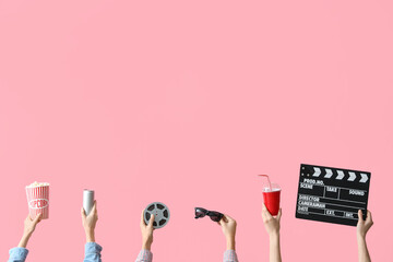 Many hands with bucket of popcorn, movie clapper and drinks on pink background
