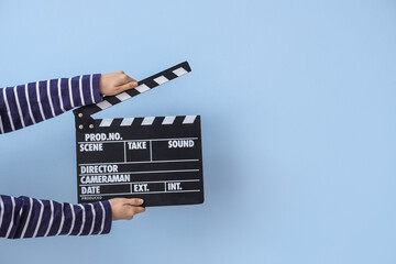 Female hands with movie clapper on blue background