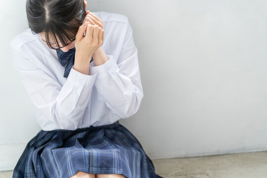 教室の隅でうずくまり怖がる女子高生・高校生・中学生（いじめ・暴力・DV・殴られる・毒親・精神病）
