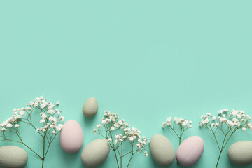 Painted Easter eggs with gypsophila flowers on turquoise background