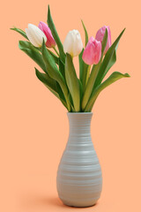 Vase with beautiful tulips on orange background. International Women's Day
