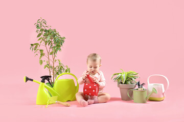 Cute baby gardener with plants and supplies on pink background
