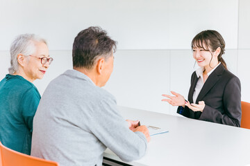 Obraz premium 高齢者夫婦の相談・カウンセリングに応じる女性ソーシャルワーカー・支援相談員・生活相談員・社会福祉士 