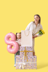 Little girl with her mother, gifts and balloon in shape of figure 8 on yellow background. International Women's Day