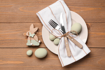 Beautiful table setting with Easter eggs, napkin and cutlery on wooden background