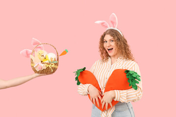 Beautiful young shocked woman in bunny ears with carrot-shaped toys and hands holding Easter basket...