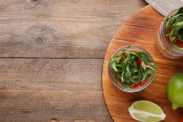 Healthy salad in glass jars on wooden table, flat lay. Space for text