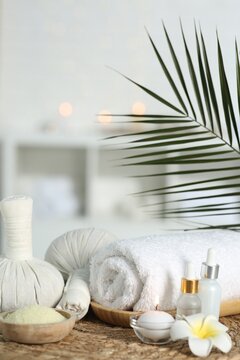 Composition with different spa products and plumeria flower on wicker mat indoors