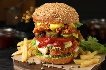Delicious burger with crispy chicken patty and french fries on table, closeup