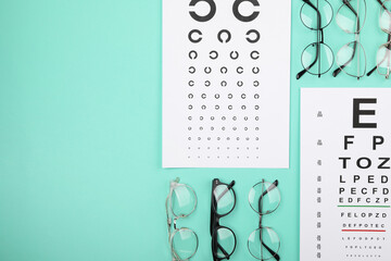 Vision test chart and glasses on turquoise background, flat lay. Space for text