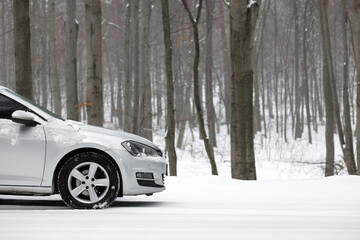 Car with winter tires on snowy road in forest, space for text