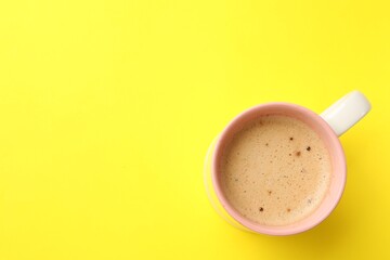 Aromatic coffee in cup on yellow background, top view. Space for text