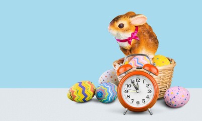 Easter concept . Alarm clock eggs ears rabbit on a blue background.
