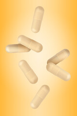 Vitamin. Capsules falling on orange gradient background