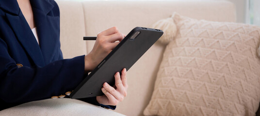Closeup hands young asian businesswoman sitting on sofa using tablet computer for planning success...