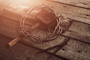 Christ a crown of thorns, on a rustic wooden surface next to a rusty nail