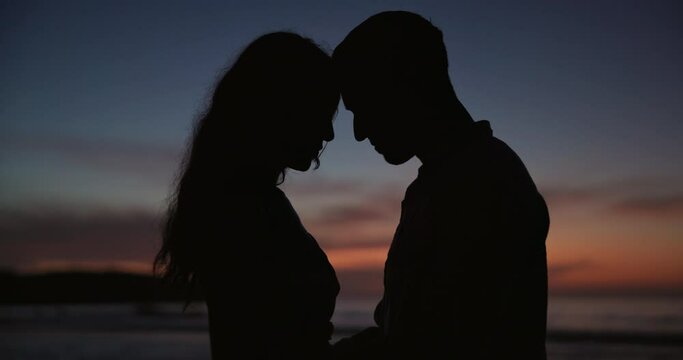Sunset, love and silhouette of couple at beach on vacation, adventure or holiday for romantic date. Travel, care and shadow of man and woman on tropical weekend trip for valentines day together.