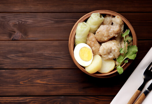 Somay or siomay, siew may, traditional indonesian street food like  fish cake dumpling and dimsum, timsum with egg, cabbage, peanut sauce served in wooden background with empty copy space for text