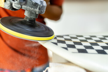 Close-up of a worker polishing a surfboard in a workshop