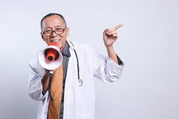 Adult Asian man doctor using megaphones announces medical news while pointing aside to empty space...