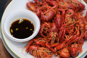 steamed red swamp crayfish with dipping vinegar sauce on plate. Chinese food