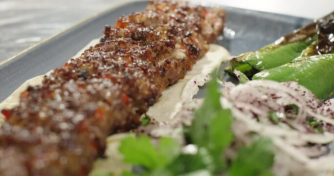 Turkish kebab barbecue on flat bread served with grilled vegetables and fresh onion. Traditional Turkish Adana kebab. Close-up