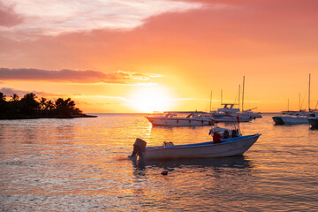 Naklejka premium Sunset scene at the ocean bay with many yachts and water taxi boats moored by the shore.