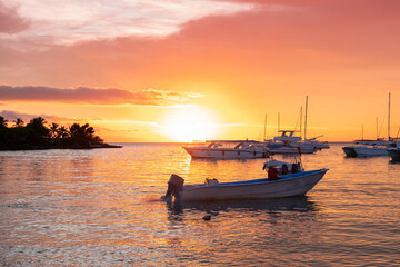 Sunset scene at the ocean bay with many yachts and water taxi boats moored by the shore.