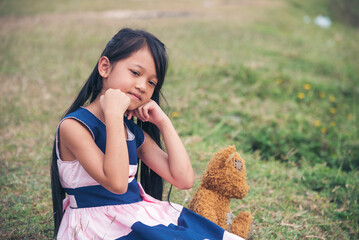 Sad girl hugging teddy bear sadness alone in green garden park. Lonely girl feeling sad unhappy...