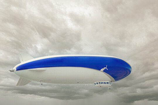 An airship with passengers on board against the backdrop of dark clouds flies over the earth.