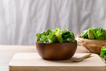 Organic cos romaine lettuce in wooden bowl, Food ingredient for healthy salad