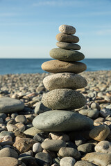 Fototapeta na wymiar Pyramid of round gray stones on the bank of a mountain river. Zen and harmony concept.Stone tower