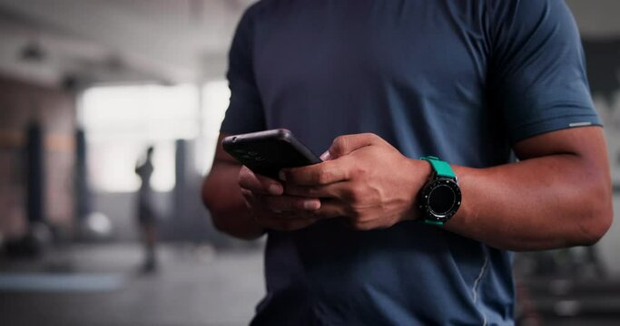 Phone, fitness and hands typing in gym for networking on social media, mobile app or internet. Technology, sports and closeup of man personal trainer or coach on cellphone for online email in studio.