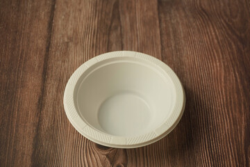 White plastic plate made of plastic on a wooden background