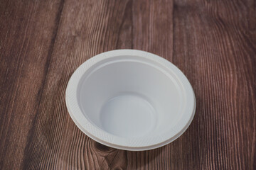 White plastic plate made of plastic on a wooden background