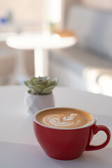 A Red Cup of Tulip Latte art Coffee on the table in the morning time
