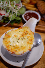 Mashed potatoes with cheese and put on a white ceramic crib dish Served on a wooden tray on a wooden table. Foods that cause fat Food for cheese lovers.