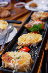 Slices of toasted bread with garlic, cheese and herbs on wooden table. Toned with color filter and soft noise to get old camera effect. Soft focus and blurred.