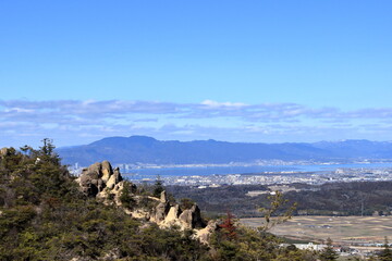 堂山の登山道にある大きな岩越しに見える比叡山と琵琶湖