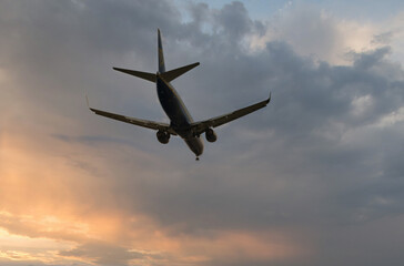 Silhouette of a civilian aircraft in a sunrise or sunset sky with beautiful clouds.	