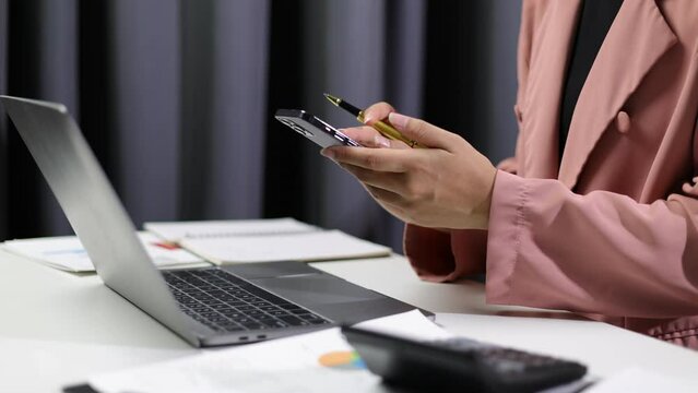 2FA login concept. Businesswoman working on laptop logging in on smartphone and modern device. Businesswoman doing paperwork in the office.