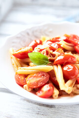 Casarecce pasta withe cherry tomatoes and fresh basil. Bright wooden background. Close up.	