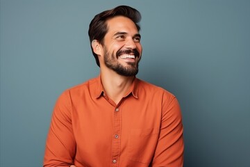 Obraz premium Portrait of a handsome young man laughing and looking at camera against blue background