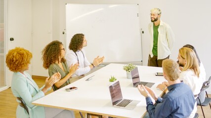 Coworkers applauding a man after a presentation using white board