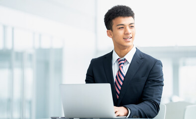 笑顔でパソコンを使う若い外国人男性ビジネスマン