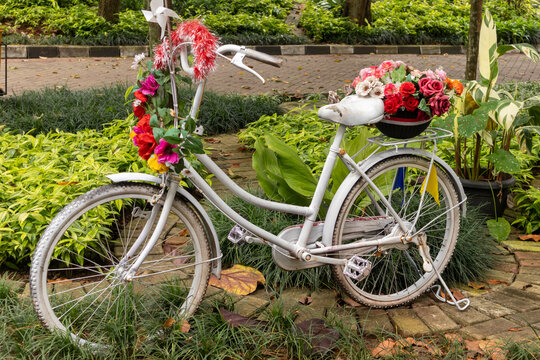 An old white vintage bicycle decorated with flowers in a park