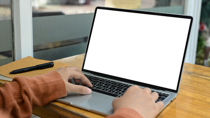 Cropped shot young woman typing on laptop keyboard with white empty screen for advertising