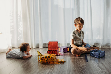Siblings  playing with toy blocks on the floor 